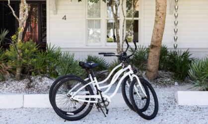 Two bicycles standing in the front of the house on the street